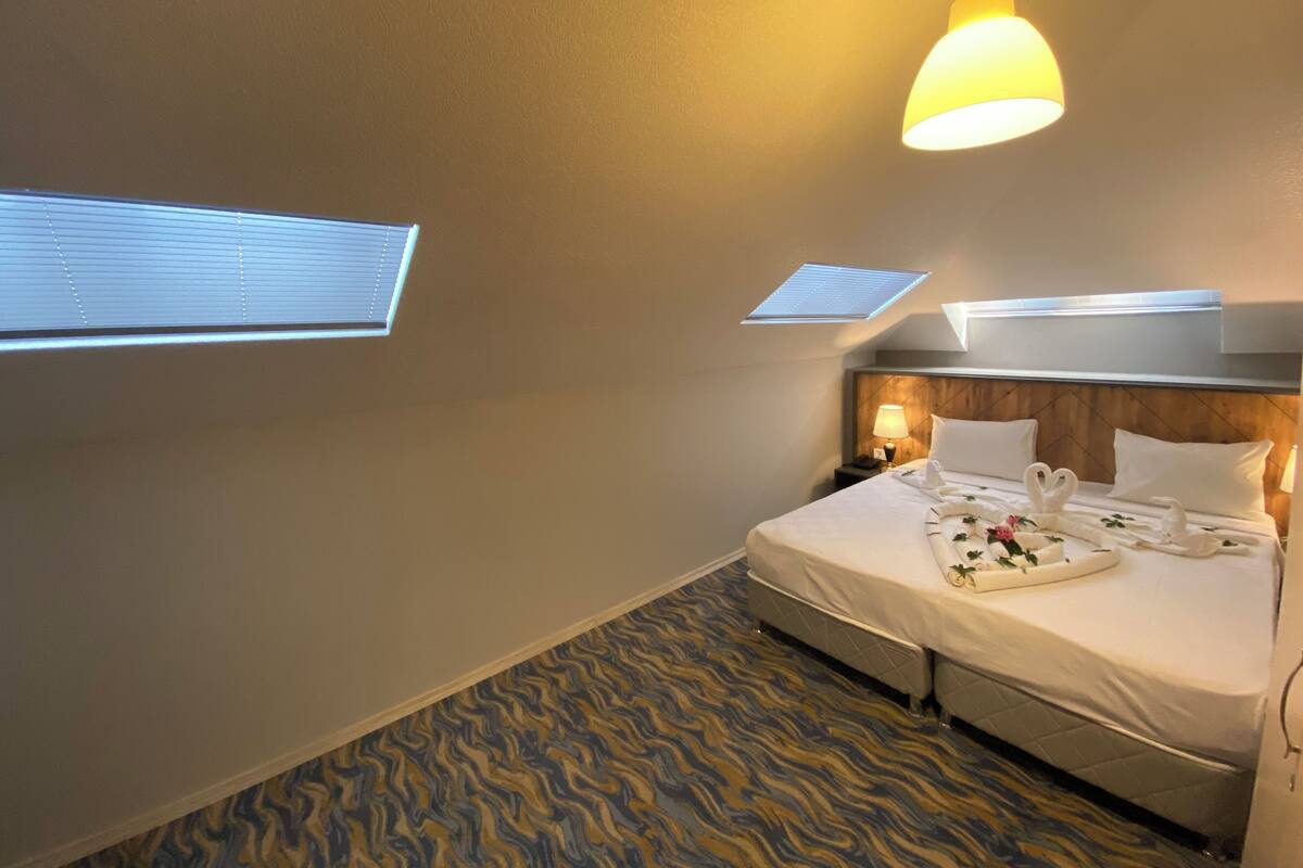 Una habitación de hotel con una cama, una mesita de noche, una lámpara y una lámpara del techo.