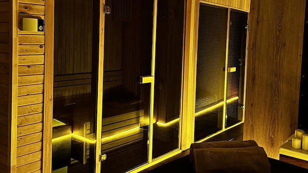 Una habitación con paneles de madera, una puerta corrediza de vidrio y un banco.
