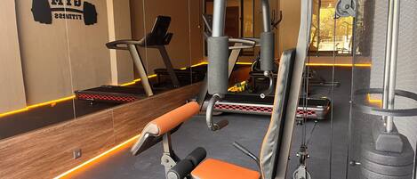 A gym with exercise equipment, a treadmill, and a wall with the text "BRIDGED HOTELS FITNESS".
