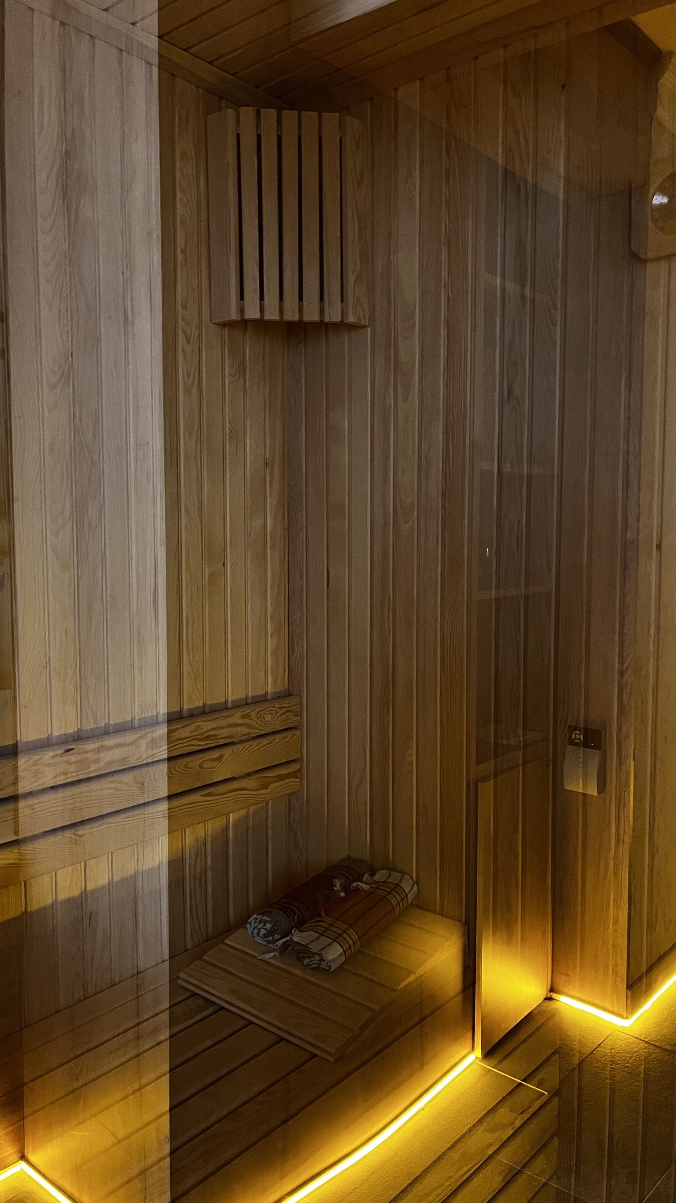 A wooden sauna with a bench and a door.