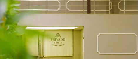 A hotel lobby with a reception desk, a seating area, and a staircase.