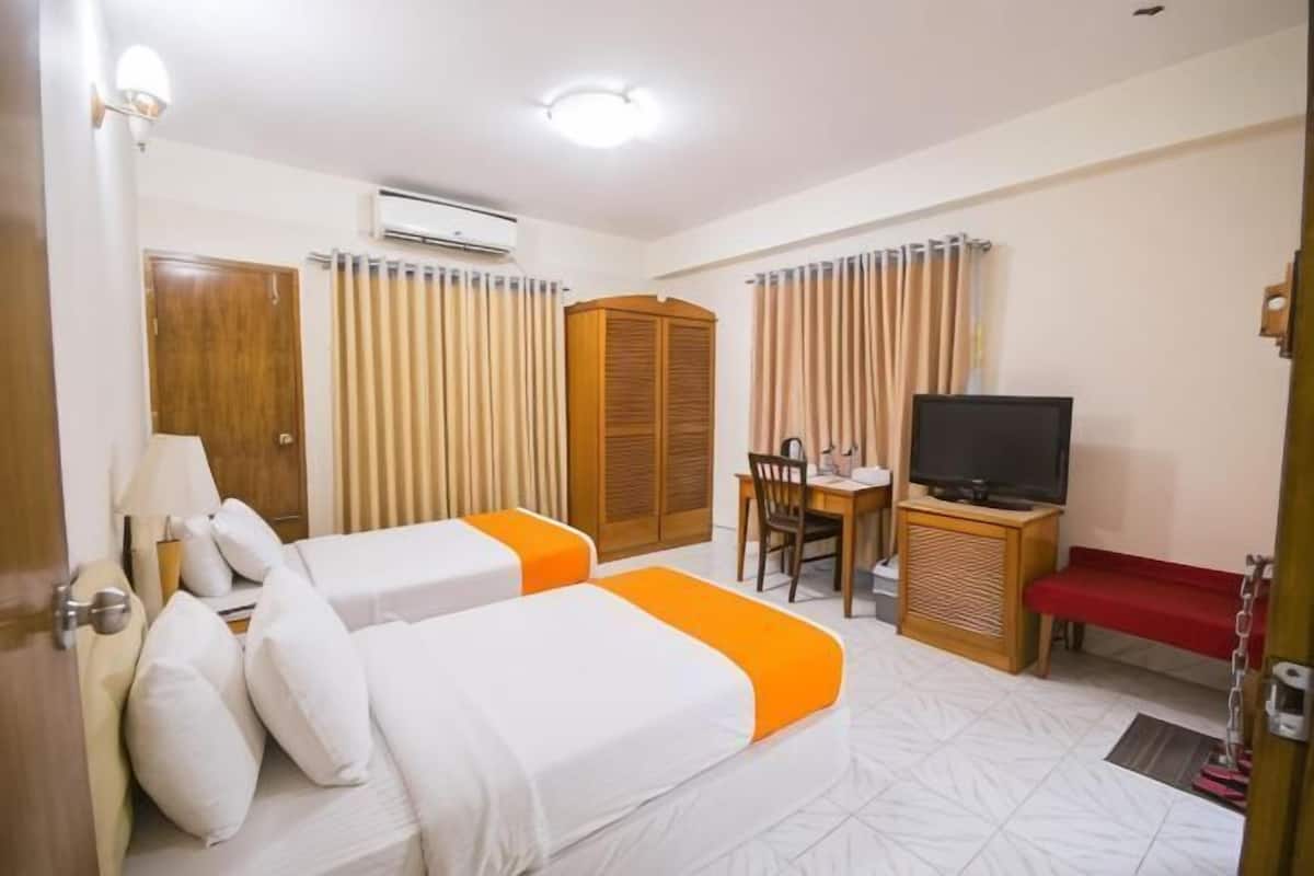 A hotel room with two beds, a desk, a television, and a wardrobe.