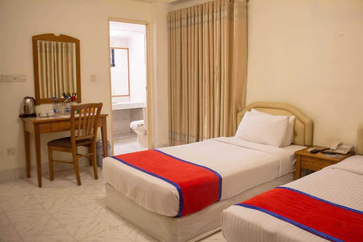 A hotel room with two beds, a desk with a chair, a mirror, a telephone, and a curtain.