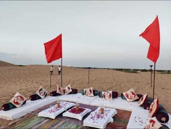 Un décor désertique avec une table dressée pour un repas, deux drapeaux rouges et une vue sur le désert en arrière-plan.