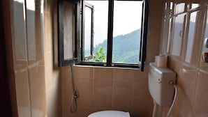 A small bathroom with a toilet, a shower, and a window.