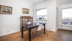Et rum med et træbord, hvide stole, et glaskab og to billeder på væggen.