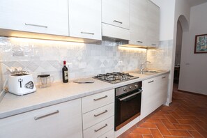 A kitchen with white cabinets, a gas stove, a toaster, and a wine bottle. - gorgeous terrace in Florence (Firenze)
