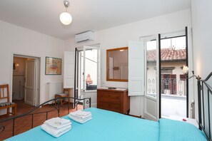 A bedroom with a bed, a dresser, a chair, and a window with a view of a building. - gorgeous terrace in Florence (Firenze)