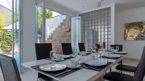 A dining area with a long table set for six, surrounded by black chairs.