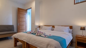 A bedroom with a bed, a wooden bench, a nightstand, and a door.