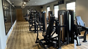 Una palestra con diverse macchine per esercizi, pavimento in legno e luci a soffitto.