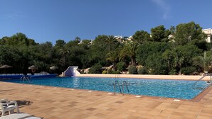 Una piscina con acqua cristallina circondata da un solarium piastrellato con lettini.