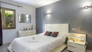 A modern bedroom with a large bed, bedside tables, a mirror, and a window with a view of greenery. - VISTA MONTE ( Francisca ). Apartment in residentail area near The beach. (Puerto Pollensa)