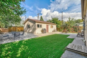 Una casa de un solo piso con un patio, césped y terraza de madera.