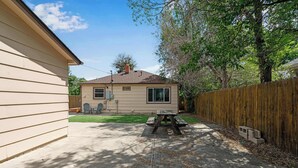 A backyard with a picnic table, a wooden fence, and a house. - 2BR Pet friendly BBQ Fire Pit in EastSide Colorado (Colorado Springs)