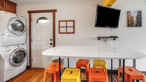 A laundry room with stacked washing machines, a white door, and a television mounted on the wall. - 2BR Pet friendly BBQ Fire Pit in EastSide Colorado (Colorado Springs)