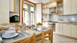A modern kitchen with wooden cabinets, a dining table set for breakfast, and a window with curtains. - Florence at one step, wifi internet, parking, A/C (Scandicci)