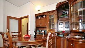 A dining area with a wooden table and chairs, a cabinet with glass doors, and a kitchen area with a stove. - Florence at one step, wifi internet, parking, A/C (Scandicci)