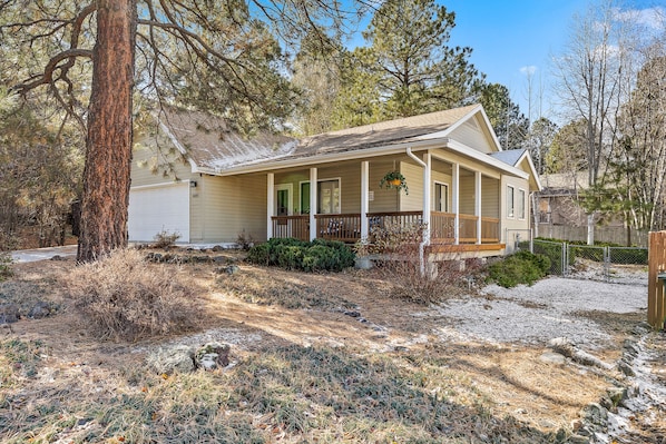 A single-story house with a porch, a garage, and a small yard with sparse vegetation.