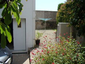 A courtyard with a potted plant, a solar panel, and a car parked outside a building.
