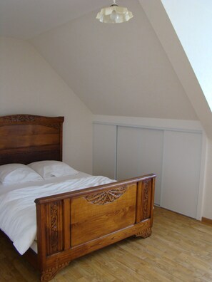 A bedroom with a wooden bed, white bedding, and a sloped ceiling.