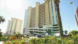 Ein mehrstöckiges Hotel mit Tiefgarage und Palmen.