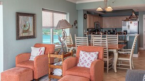 Ein Wohnzimmer mit zwei orangefarbenen Sesseln, einem Holztisch und einem Essbereich mit einem Holztisch und Stühlen.