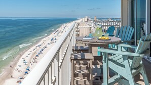 Ein Balkon mit Blick auf Strand und Meer, ausgestattet mit Sitzgelegenheit und einem Tisch mit einem Getränk.