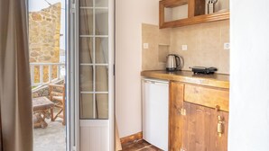 Una cucina con parete in pietra, pensili in legno e lavastoviglie.