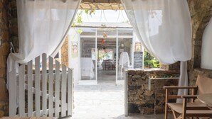 Un'area pranzo all'aperto con pareti in pietra, tende bianche e un recinto in legno.