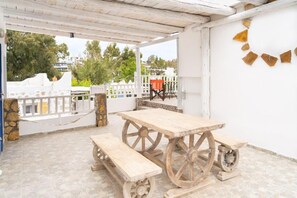 Un patio al aire libre con una mesa y bancos de madera, una valla blanca y vistas del entorno.