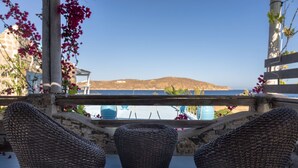 Una terrazza con mobili in vimini, vista sul mare e un paesaggio montuoso sullo sfondo.