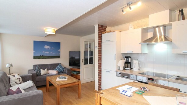 A compact living space with a sofa, a coffee table, a TV, and a kitchenette with modern appliances. - Centrally located apartment for 4 people and dog (Greetsiel)