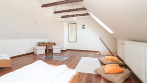A spacious attic bedroom with wooden beams, a large window, a bed, a small table, and a radiator. - Centrally located apartment for 4 people and dog (Greetsiel)