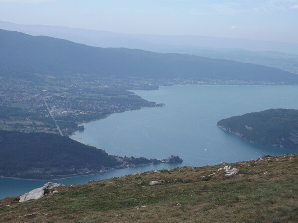 Vista panorámica de un lago rodeado de colinas y un pequeño pueblo.