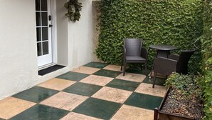Un patio a cuadros con muebles de exterior, una puerta y un muro cubierto de vegetación.