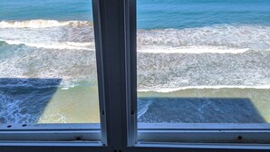 Ein Zimmer mit großem Fenster und Meerblick, Wellen vor der Küste.