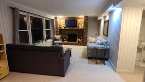 A cozy living room with a dark sofa, a small table, and a fireplace.