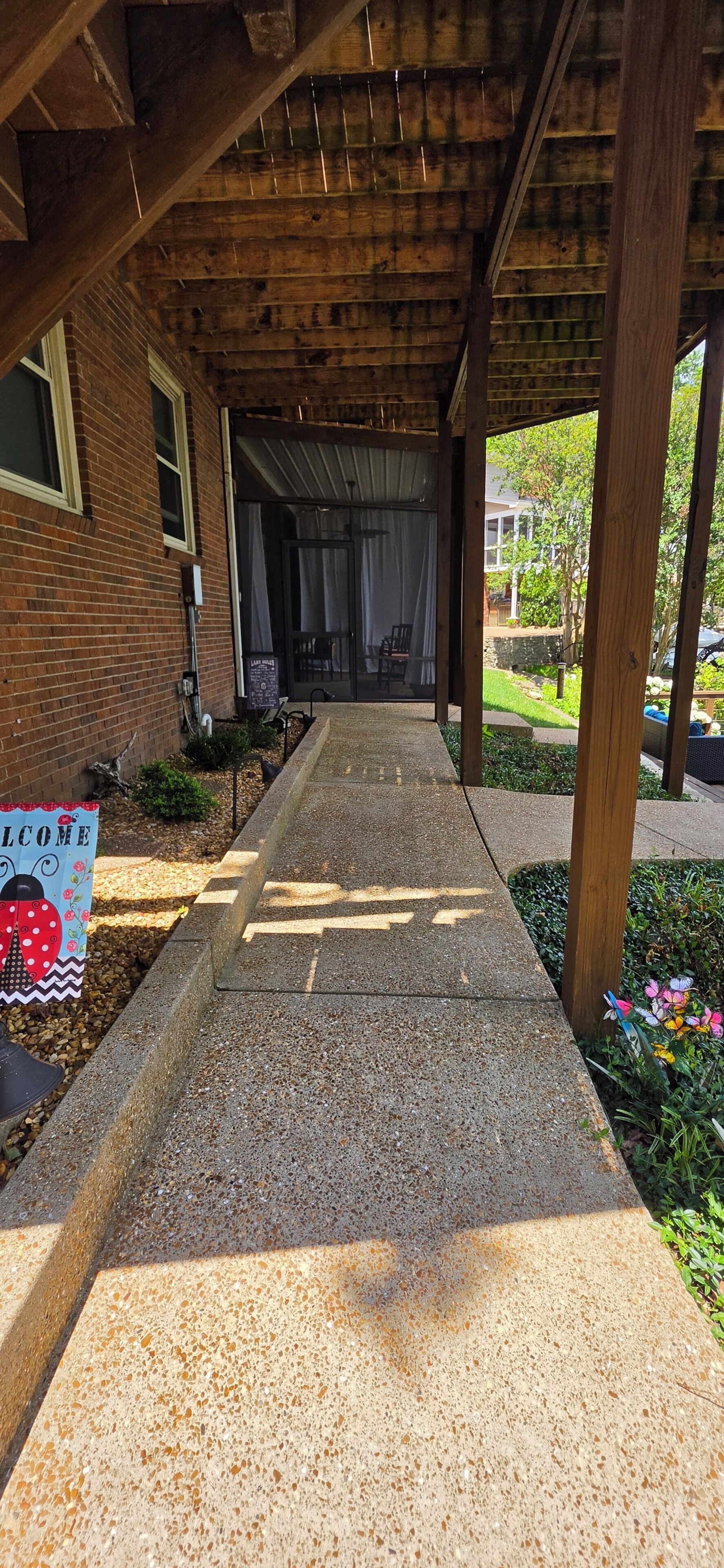 A covered walkway leading to a building with a brick facade and a welcome sign.