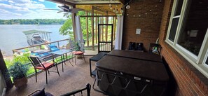 A balcony with a view of a lake, outdoor seating, and a grill.