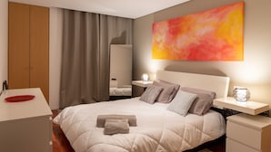 A modern bedroom with a large bed, bedside tables, a desk, and a large abstract painting on the wall. - Porto H Dragão (Porto)