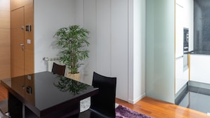 A modern dining area with a glass table, black chairs, a potted plant, and a purple rug. - Porto H Dragão (Porto)
