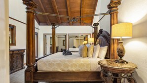 Un lit à baldaquin en bois, une table ronde avec une lampe et un miroir au-dessus du lit.