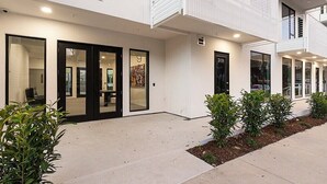 A modern building with a white facade, large glass windows, and a visible entrance. - ILLUME/Modern New Condo/ Pool & Downtown Views/Gym (Nashville)