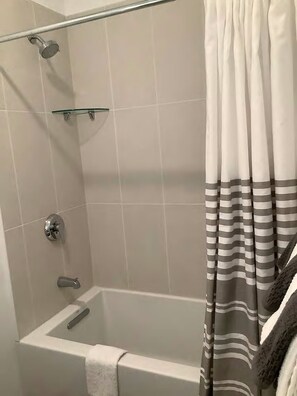 Een bad/douchecombinatie, een haardroger, handdoeken, toiletpapier