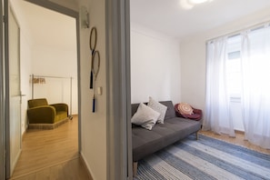 Un salon moderne avec un canapé gris, des coussins à motifs et un tapis à rayures bleues.