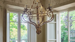A dining area with a round wooden table, six chairs, and a decorative chandelier. - Ancient Villa Art Nouveau original, large park and pool at 3 Km from Lucca Walls (Capannori)