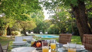 An outdoor dining area with a pool in the background, surrounded by lush greenery and wicker furniture. - Ancient Villa Art Nouveau original, large park and pool at 3 Km from Lucca Walls (Capannori)