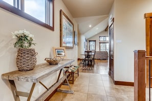 A hallway with a wooden bench, a wicker basket, a framed welcome sign, and a framed map on the wall.