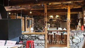 A rustic interior with a stone wall, wooden furniture, and a cozy seating area.
